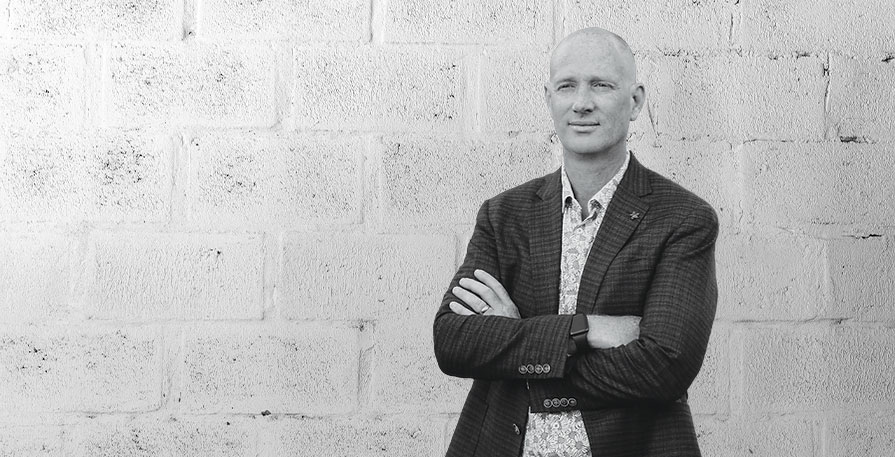 Biotechnologist and founder of SRW Laboratories Greg Macpherson arms crossed in front of a brick building