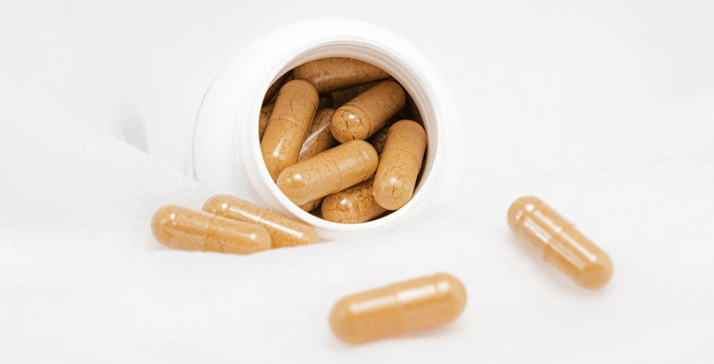 white background with a white pill bottle and capsules with brown powder inside